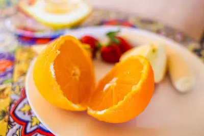 an orange cut in half on a plate with fruit at B&B Giardino dei Cedri in Trabia