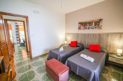 a hotel room with two beds and a chair at B&B Giardino dei Cedri in Trabia
