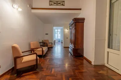 a living room with wooden floors and a room with chairs at MARIANO APARTMENT Palermo in Palermo
