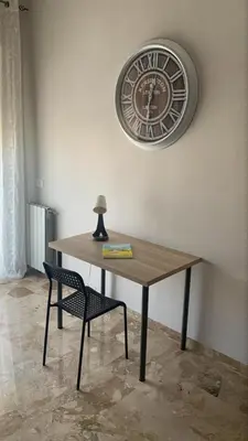 a table with a chair and a clock on the wall at D'Kasa Mia Capaci in Capaci