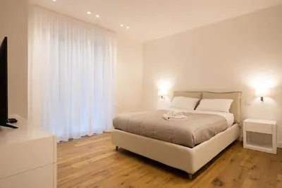 a white bedroom with a bed and a television at Luxury Libertà in Palermo