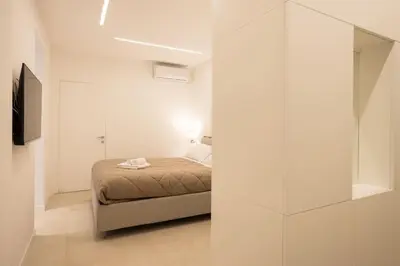 a white bedroom with a bed and a glass wall at Luxury Libertà in Palermo
