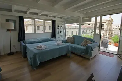 a living room with a bed and a couch and windows at Stunning Kalsa in Palermo