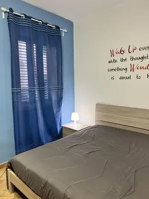 a bedroom with a bed and a blue curtain at Casa Niní in Campofelice di Roccella