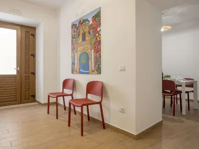 a dining room with red chairs and a painting on the wall at Apartment Sole by Interhome in Balestrate