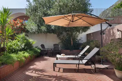 a patio with an umbrella and a table and chairs at Hector's House by DomuSicily in Palermo