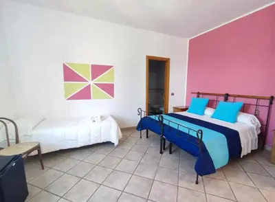 a bedroom with two beds and a pink wall at Allegroitalia Torre Artale Palermo in Trabia