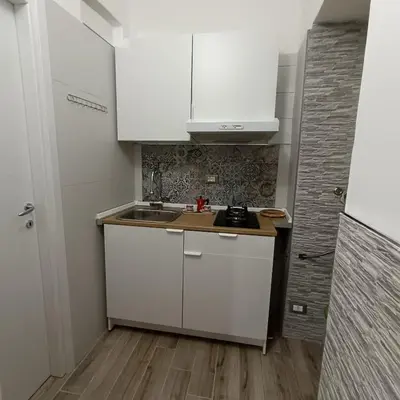 a small kitchen with white cabinets and a sink at Casa alla Stazione in Palermo