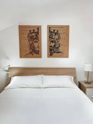 a bedroom with a white bed with two pictures on the wall at Casa di Giulietta in Palermo