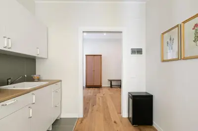 a kitchen with white cabinets and a black refrigerator at GuestHost - NotHotel Palermo Central Bright Apartment in Palermo