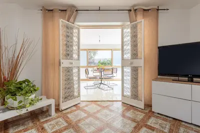 an open living room with a tv and a table at Casa in Villa a Mondello-700m dal mare in Palermo
