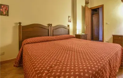 a bedroom with a large bed with a orange comforter at Rosmarino in San Giuseppe Jato
