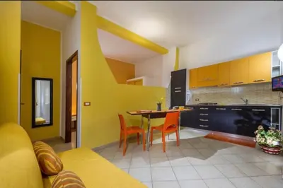 a kitchen with yellow cabinets and a table and chairs at Principe Tancredi in Castellammare del Golfo
