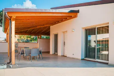 a patio with a wooden pergola and a table and chairs at Villa Laura in Cefalù