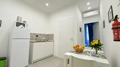 a white kitchen with a table and a refrigerator at Palermo Central in Palermo