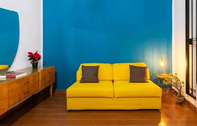 a yellow couch in a living room with a blue wall at DaMé in Palermo