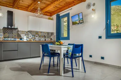 a kitchen with a white table and blue chairs at Villa Holidays in Torre Bennistra in Scopello