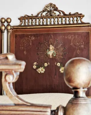 a bed with a wooden headboard with a painting on it at Casa Al Plumbago in Termini Imerese