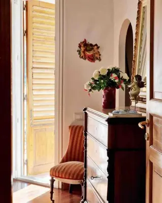 a room with a dresser and a chair and a vase of flowers at Casa Al Plumbago in Termini Imerese