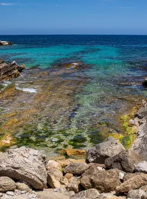 a beach with rocks and the ocean in the background at Ciuri Ciuri in Isola delle Femmine