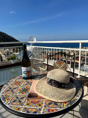 a table with a hat and a bottle of wine on a balcony at La Terrazza sul Golfo in Castellammare del Golfo