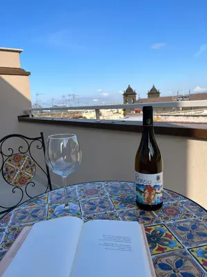a bottle of wine and a book on a table with a glass at La Terrazza sul Golfo in Castellammare del Golfo