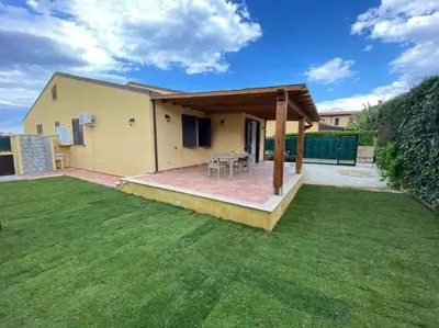 a house with a patio with a grass yard at Villa indipendente le coccinelle beach mare piscina a 250 mt dal mare con servizio di piscina a 400 mt 12 k da Cefalu in Campofelice di Roccella
