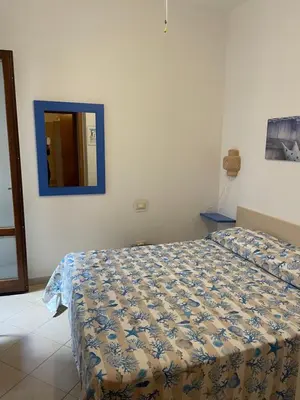 a bedroom with a bed and a mirror on the wall at Belmare trilocale a piano terra indipendente in San Vito lo Capo