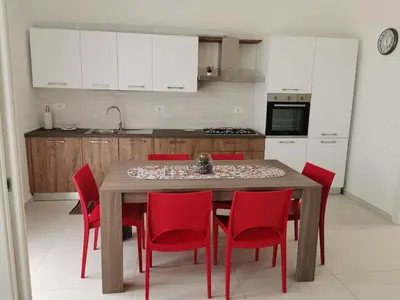 a kitchen with a wooden table and red chairs at Lovely apartment in Castellammare del Golfo in Castellammare del Golfo
