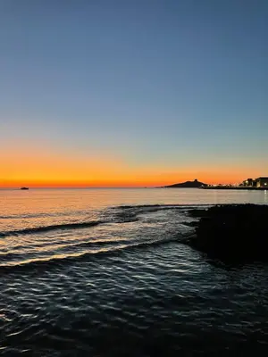 a beach with the sun setting in the ocean at Casa Chiara in Isola delle Femmine