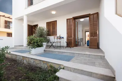 a front porch of a house with a wooden door at I Tre Golfi - Via Salvatore Quasimodo in San Vito lo Capo