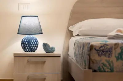 a blue and white vase on a night stand next to a bed at I Tre Golfi - Via Salvatore Quasimodo in San Vito lo Capo