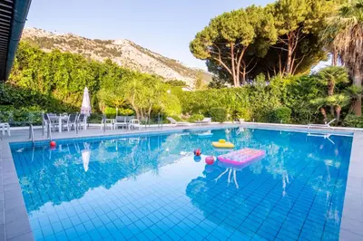 a swimming pool with a pink chair in the water at Mondello luxury villa con piscina in Mondello