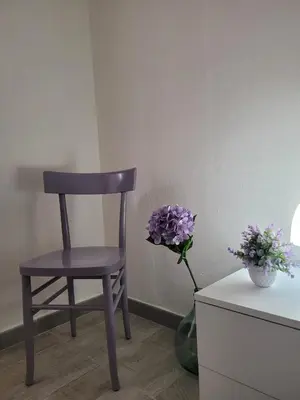 a wooden chair sitting next to a vase with purple flowers at Casa Vacanze L'Ortensia in Bagheria