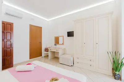 a white room with a bed and a desk at B&B Le Ortensie in San Vito lo Capo
