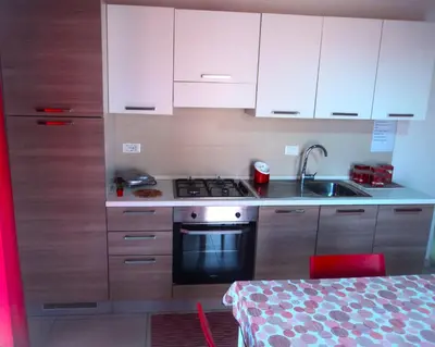 a kitchen with white cabinets and a stove and a sink at Purple House a Castellammare del Golfo in Castellammare del Golfo