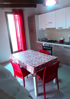 a kitchen with a table with red chairs and a kitchen with a stove at Purple House a Castellammare del Golfo in Castellammare del Golfo