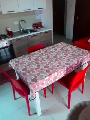 a kitchen with a table with red chairs and a table cloth at Purple House a Castellammare del Golfo in Castellammare del Golfo