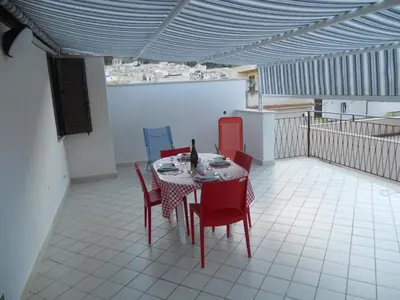 a room with a table and chairs on a balcony at Purple House a Castellammare del Golfo in Castellammare del Golfo
