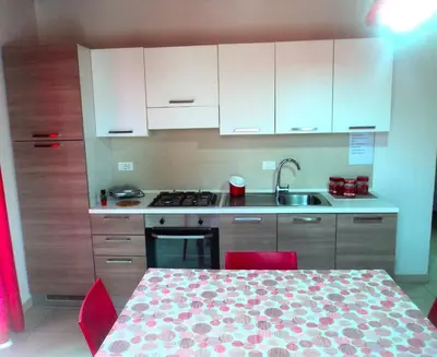 a kitchen with a table with red chairs and a sink at Purple House a Castellammare del Golfo in Castellammare del Golfo