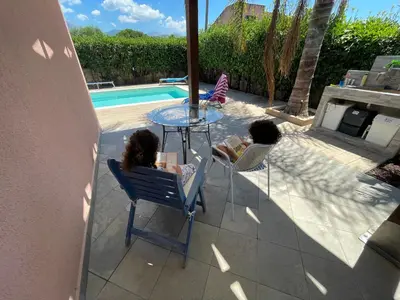 two children sitting at a table next to a pool at Villa con piscina privata riscaldata ad uso esclusivo vicino Cefalù in Lascari
