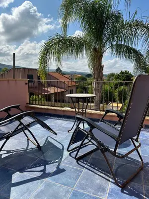 two chairs and a table on a patio with a palm tree at Villa con piscina privata riscaldata ad uso esclusivo vicino Cefalù in Lascari