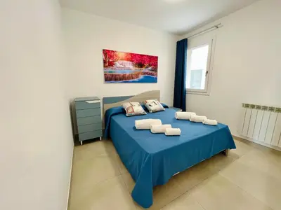 a bedroom with a blue bed and a painting on the wall at Meravigghia in Terrasini