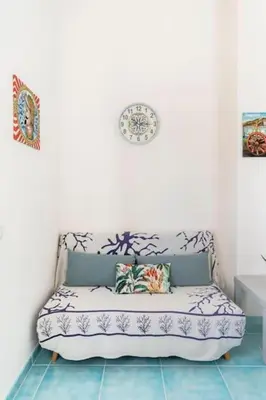 a couch in a room with a clock on the wall at Casa Mare me' in Mondello