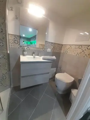 a bathroom with a toilet and a sink and a mirror at House Under Arch in Palermo