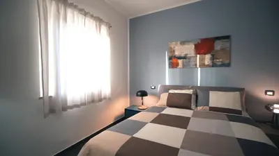 a bedroom with a bed with a checkered blanket and a window at Mi Tierra Luxury Apartments in Palermo