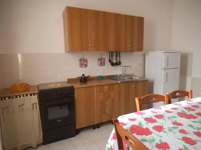 a kitchen with wooden cabinets and a stove and a table at CASA Mare & Monti PG Climatizzata in Castellammare del Golfo