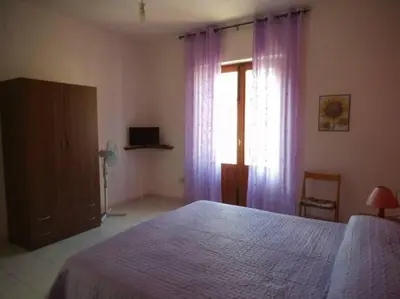 a bedroom with a bed and a window with purple curtains at Mansarda M&M DX Climatizzata in Castellammare del Golfo