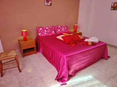 a pink bed in a room with a table and lamp at DernaFlat 15 Climatizzata in Castellammare del Golfo