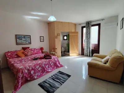a bedroom with a pink bed and a couch at Casa Derna 25dx Climatizzata in Castellammare del Golfo